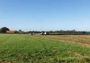 Boerderij in het landschap met een machine op het land