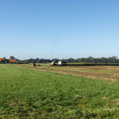 Boerderij in het landschap met een machine op het land